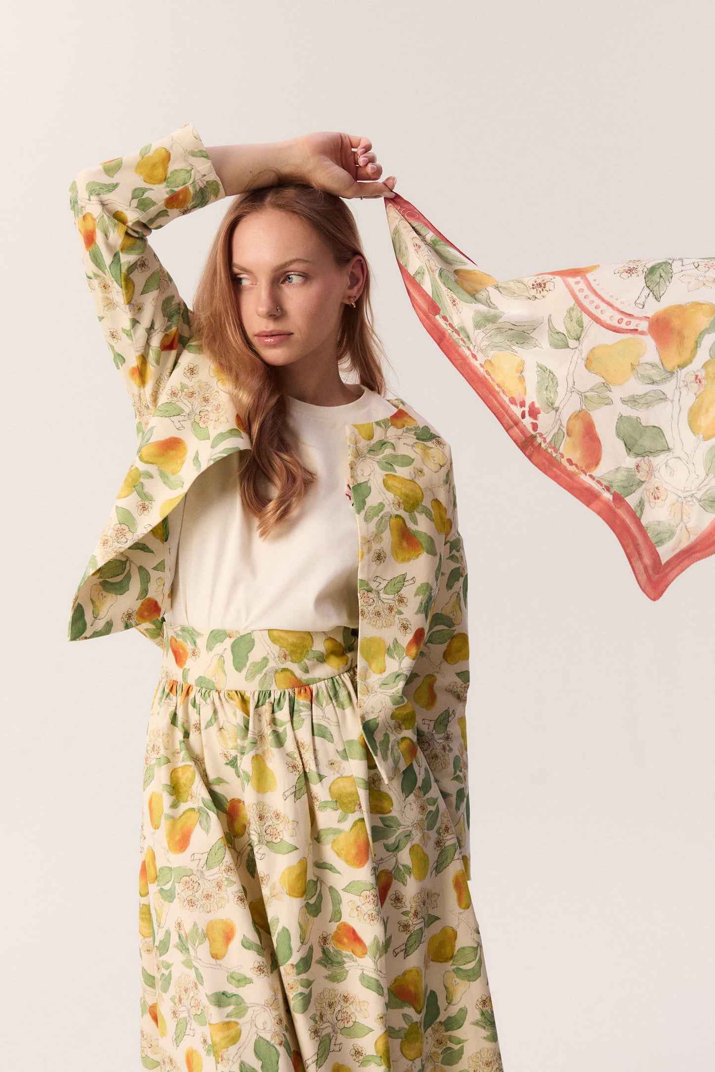 Modelka w stylizacji MAG NOLLY z apaszką w print gruszek – detal z ręką uniesioną nad głowę.