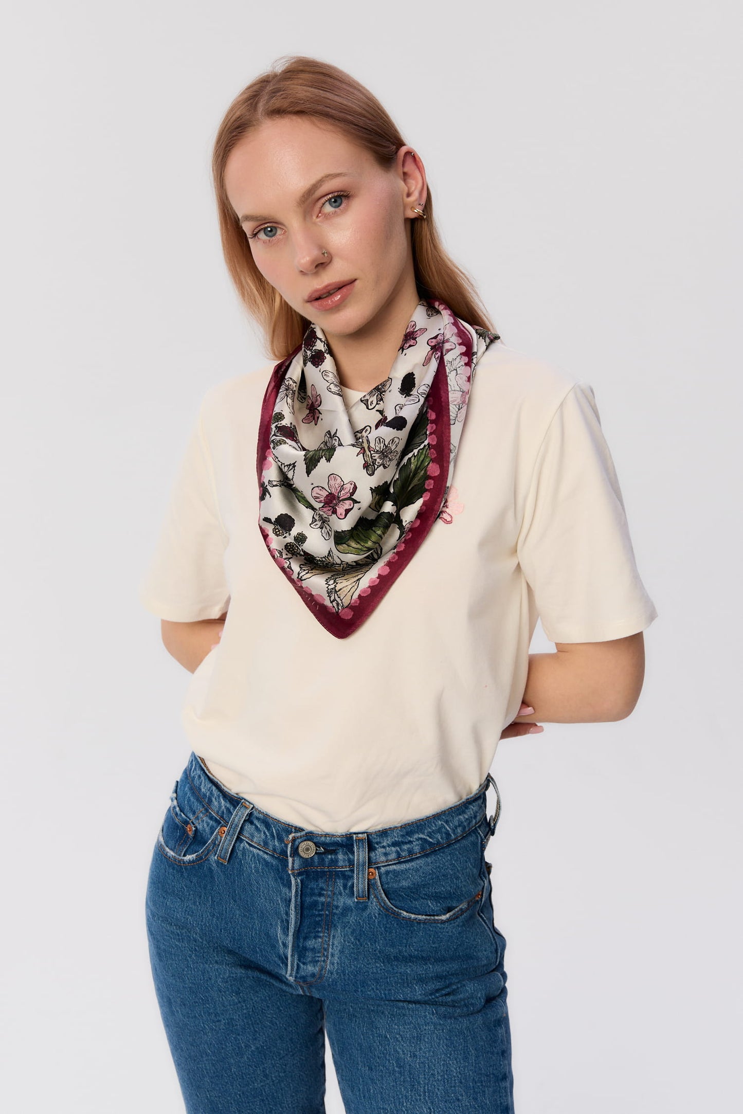 Modelka w białym t-shircie i dżinsach, z apaszką MAG NOLLY z jedwabiu we wzór jeżyn z bordową ramką, zawiązaną na szyi.