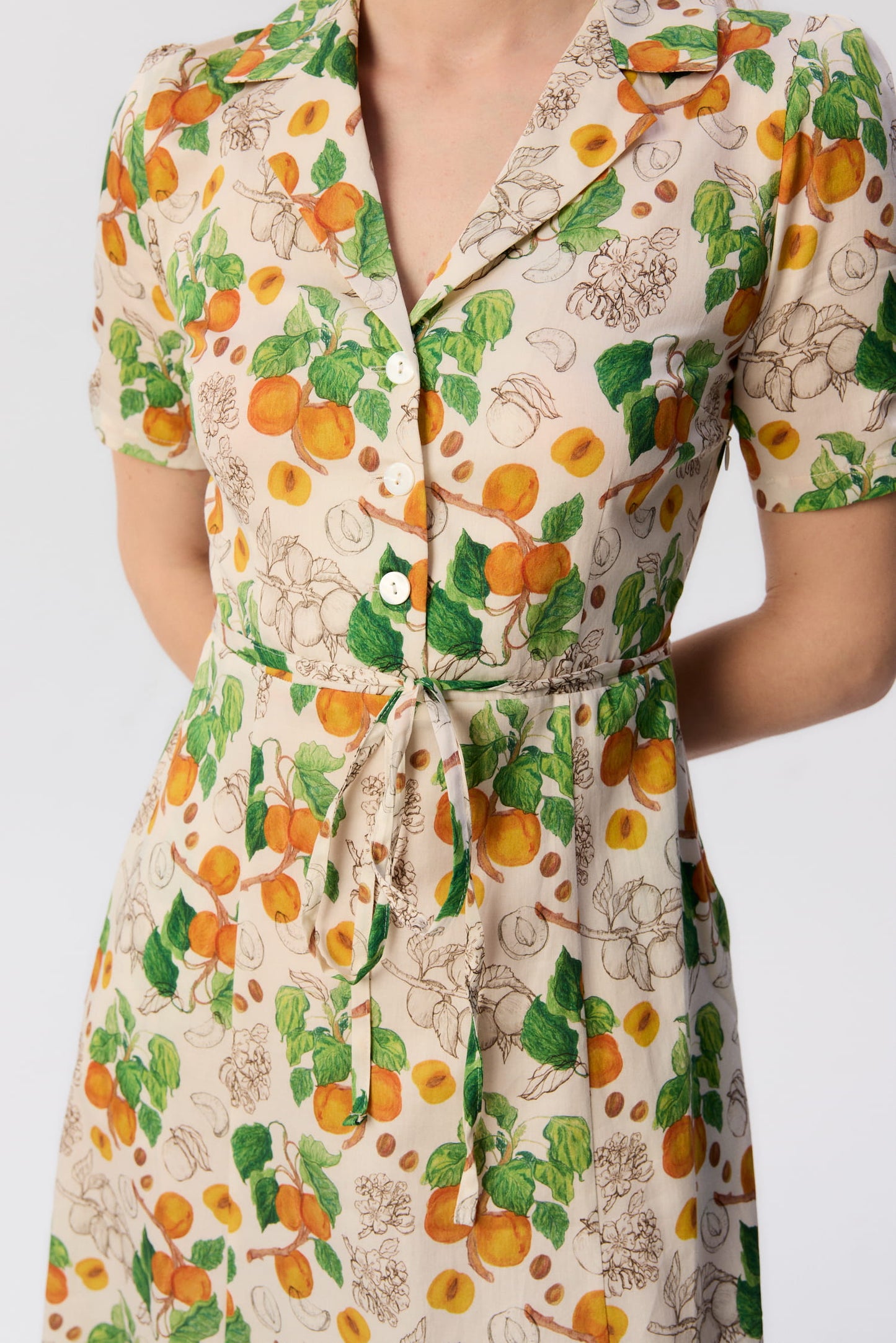 Zbliżenie na sukienkę Bellucci – print morele, guziki, pasek w talii, detal dekoltu i kołnierzyka.