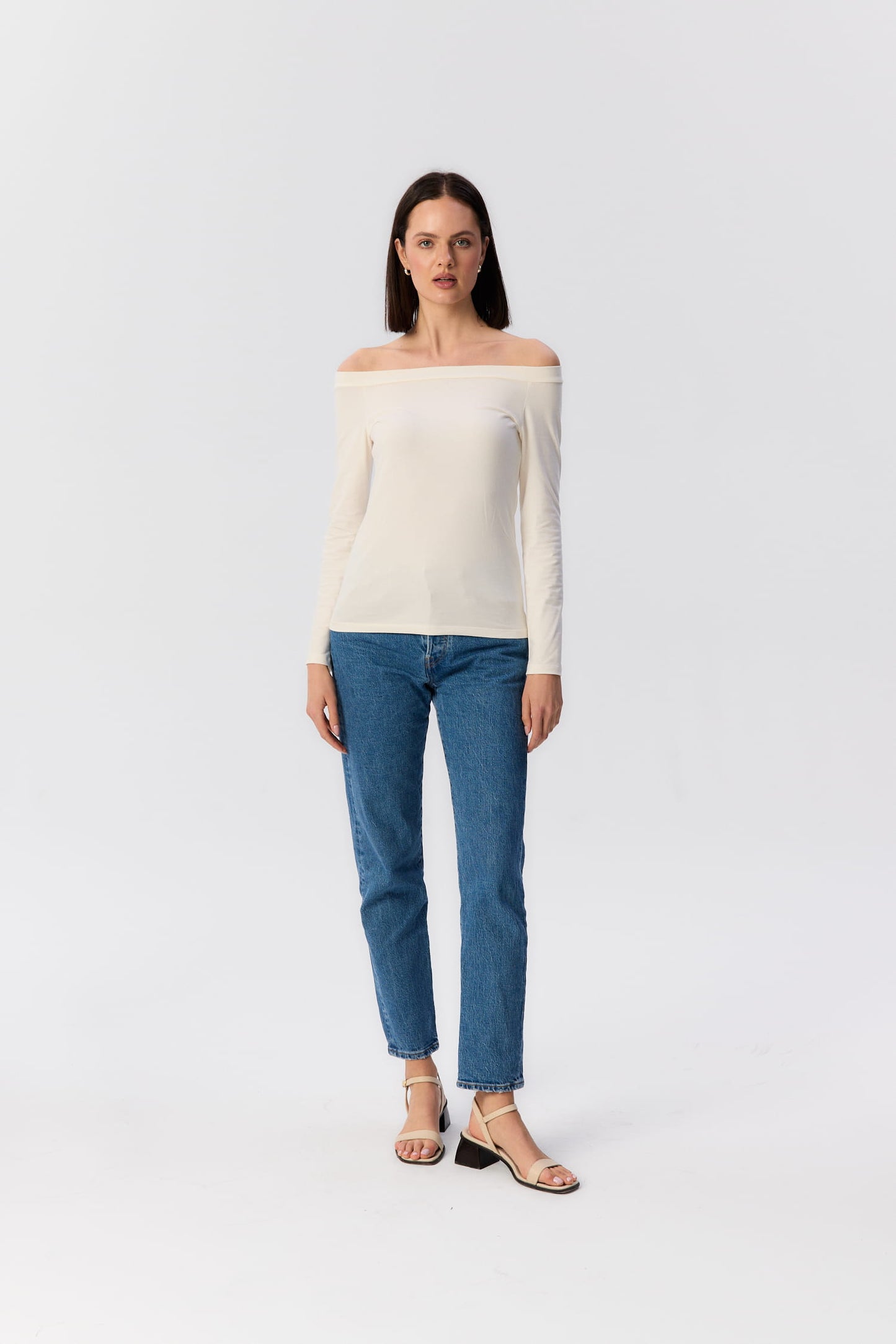 Modelka w kremowym longsleeve’ie Mori z dekoltem odsłaniającym ramiona, zestawionym z jeansami – klasyczny look MAG NOLLY.