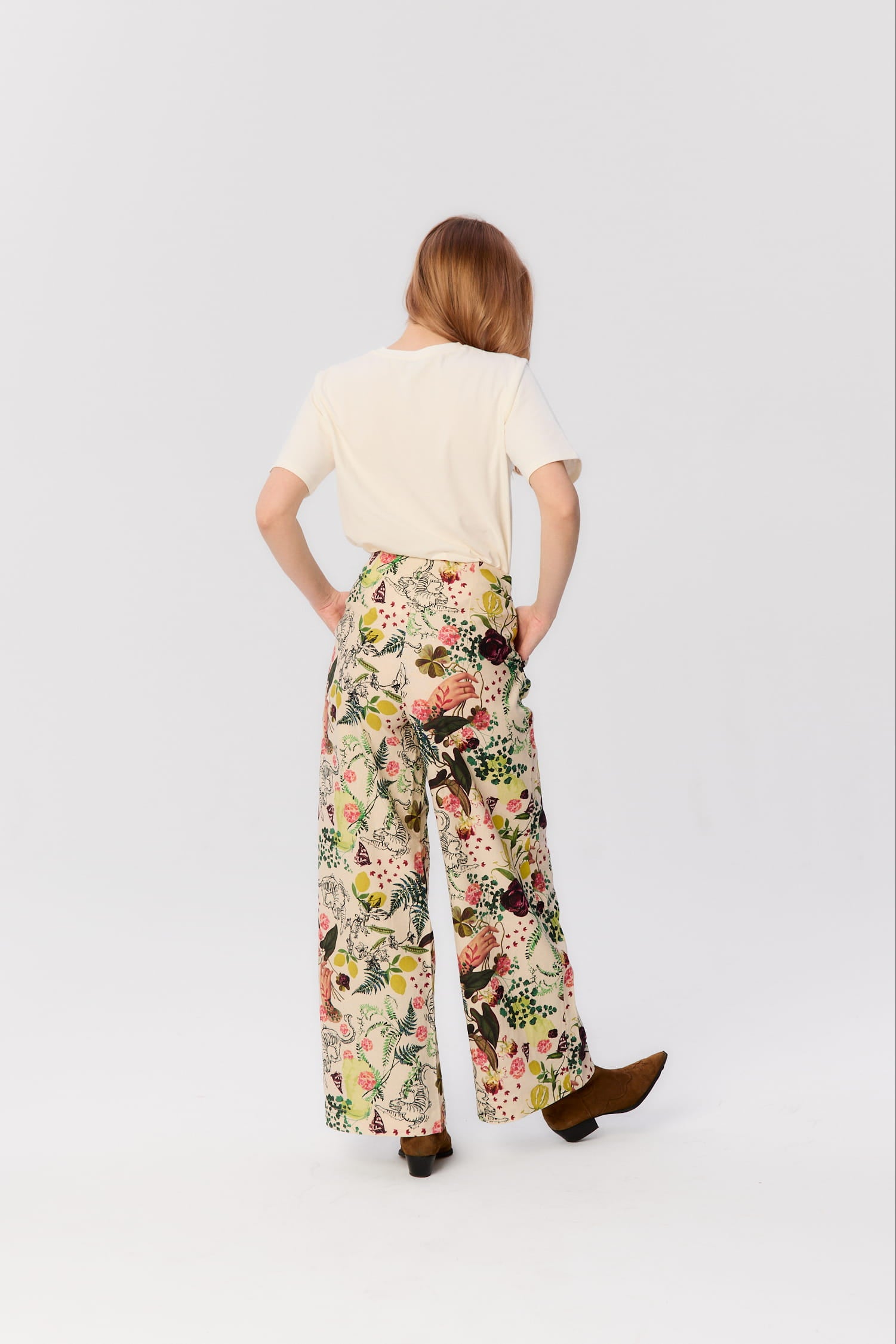 Modelka tyłem w spodniach MAG NOLLY Cardinale z printem Abstrakcja – szeroka nogawka i podwyższony stan.