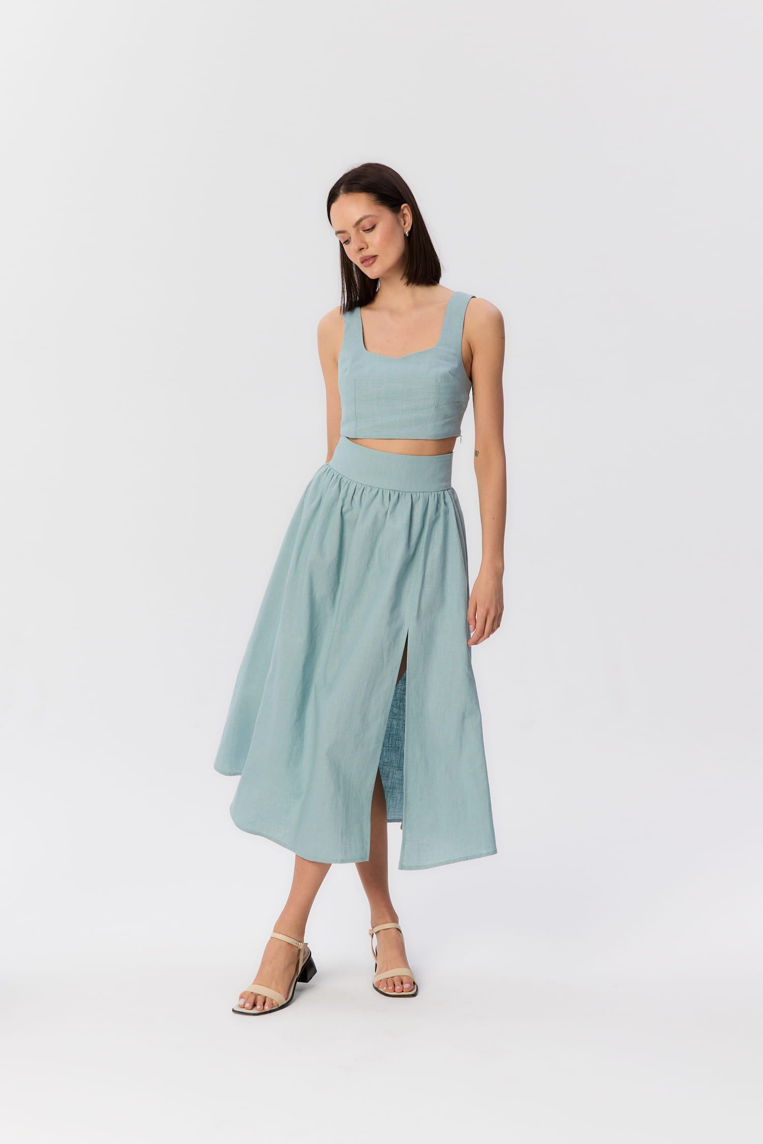 Modelka w turkusowym komplecie Milo i Sandrelli – top i spódnica midi z rozcięciem.