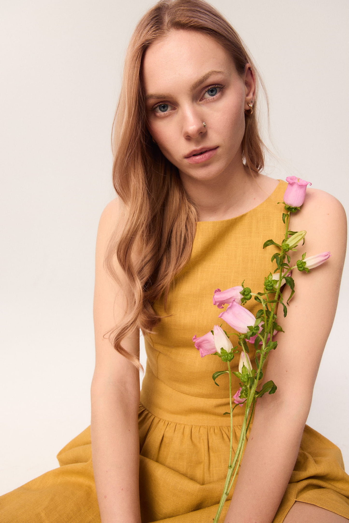 Modelka w topie MAG NOLLY Loren w odcieniu ochry, trzymająca różowe kwiaty.