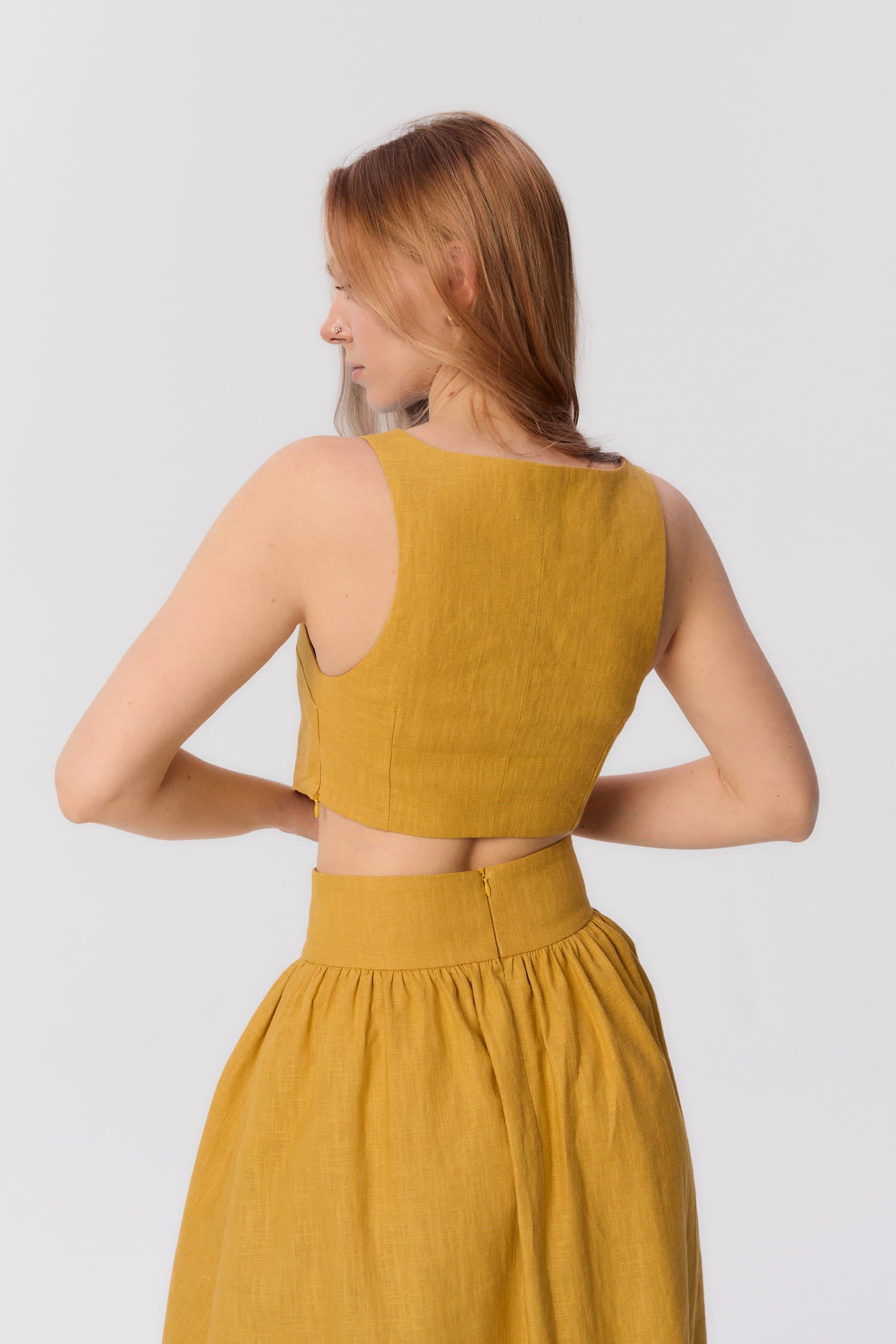 Tył topu MAG NOLLY Loren w kolorze ochry, widok na wycięcie na plecach i talię modelki.