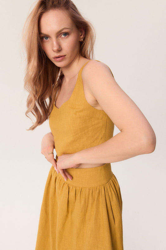 Top MAG NOLLY Milo w kolorze ochry, z widocznym wycięciem przy dekolcie i dopasowanym fasonem.