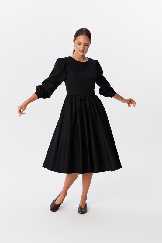 Sukienka Leone w czerni, długość midi, z bufkami i rozkloszowanym dołem, modelka w balerinach – MAG NOLLY