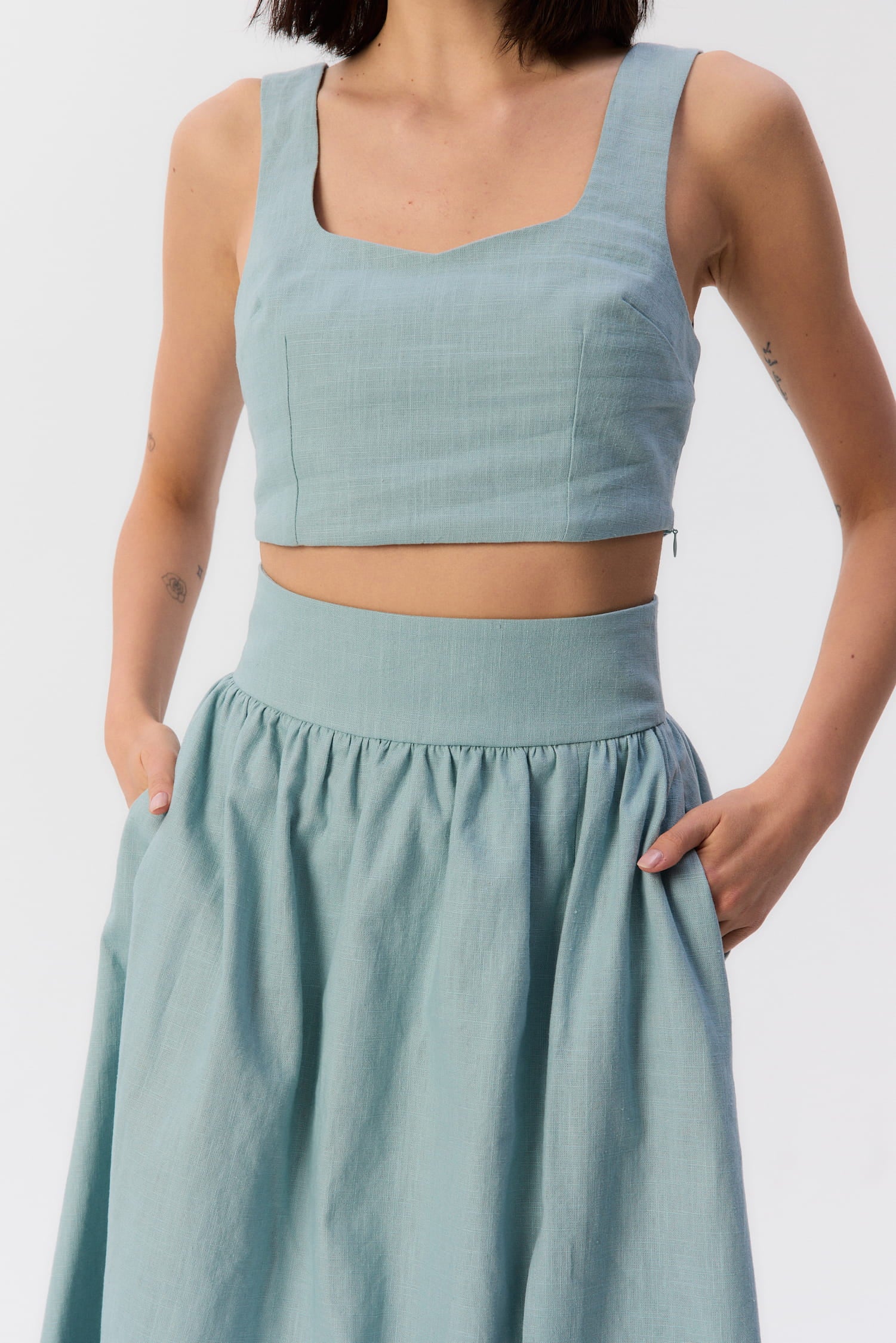 Zbliżenie na top Milo i spódnicę Sandrelli w kolorze turkusowym – letni komplet z podkreśloną talią i dekoltem.