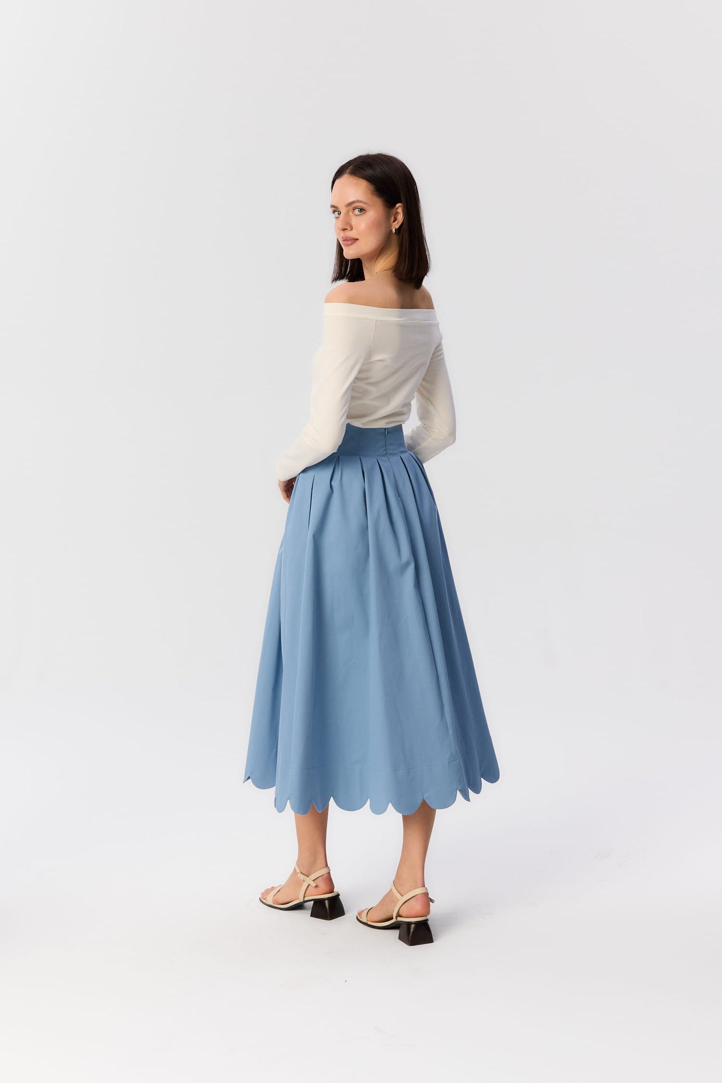 Modelka w niebieskiej spódnicy midi Fala od MAG NOLLY – widok z tyłu, falowany dół i zaznaczona talia w lekkiej stylizacji.