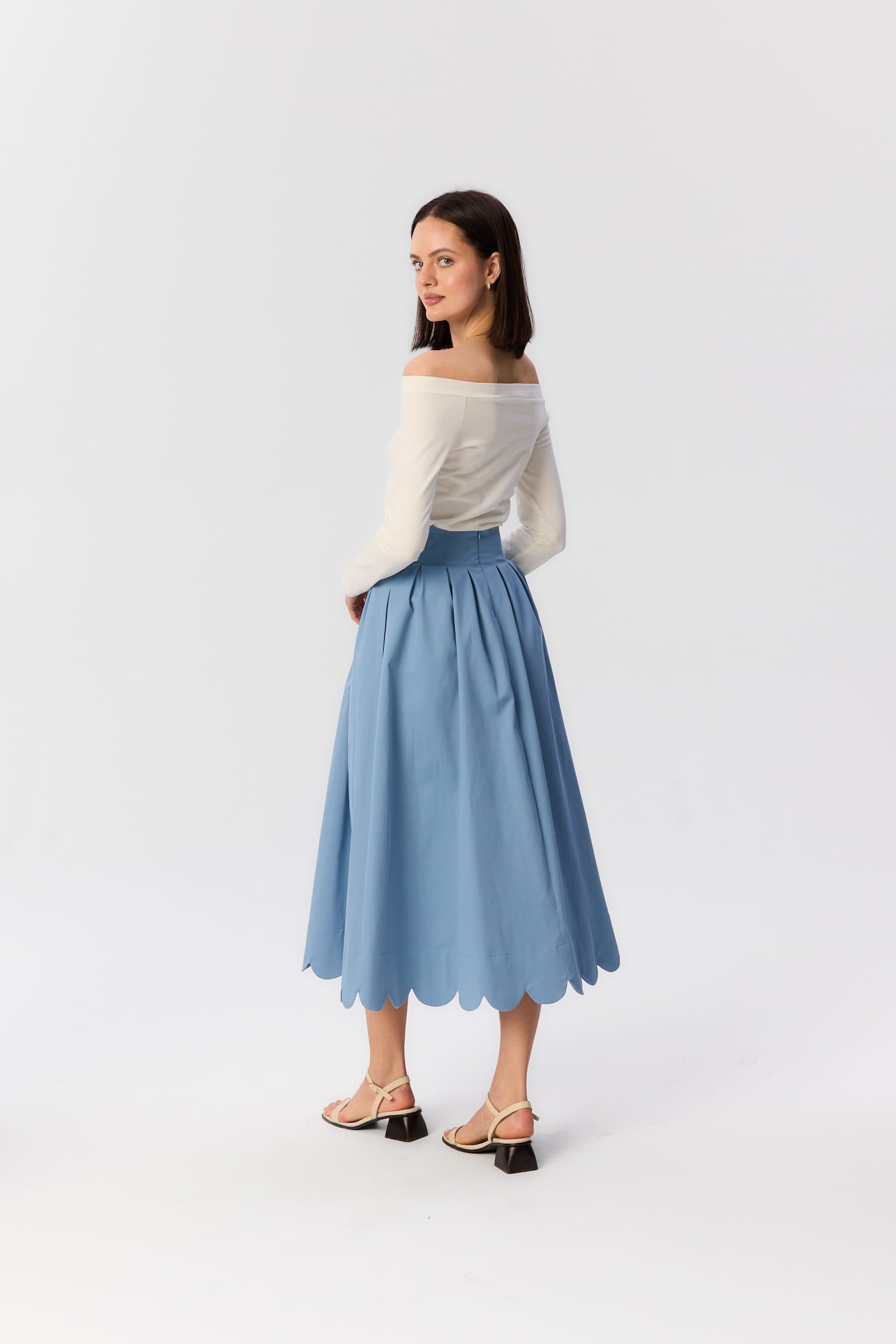 Modelka w niebieskiej spódnicy midi Fala od MAG NOLLY – widok z tyłu, falowany dół i zaznaczona talia w lekkiej stylizacji.