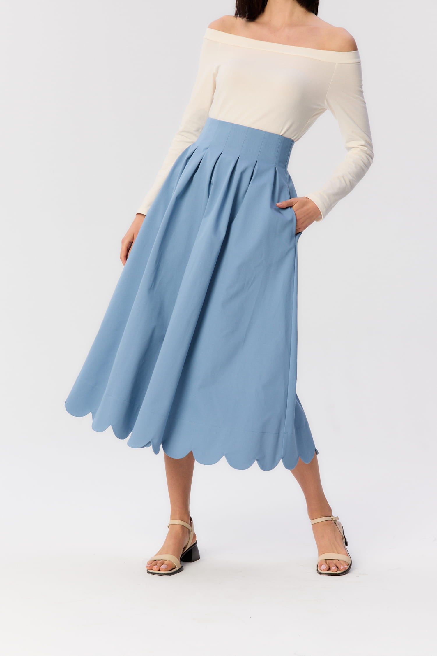 Zbliżenie na spódnicę Fala MAG NOLLY – niebieska bawełniana midi z kieszenią i falowanym wykończeniem, w lekkim ruchu.