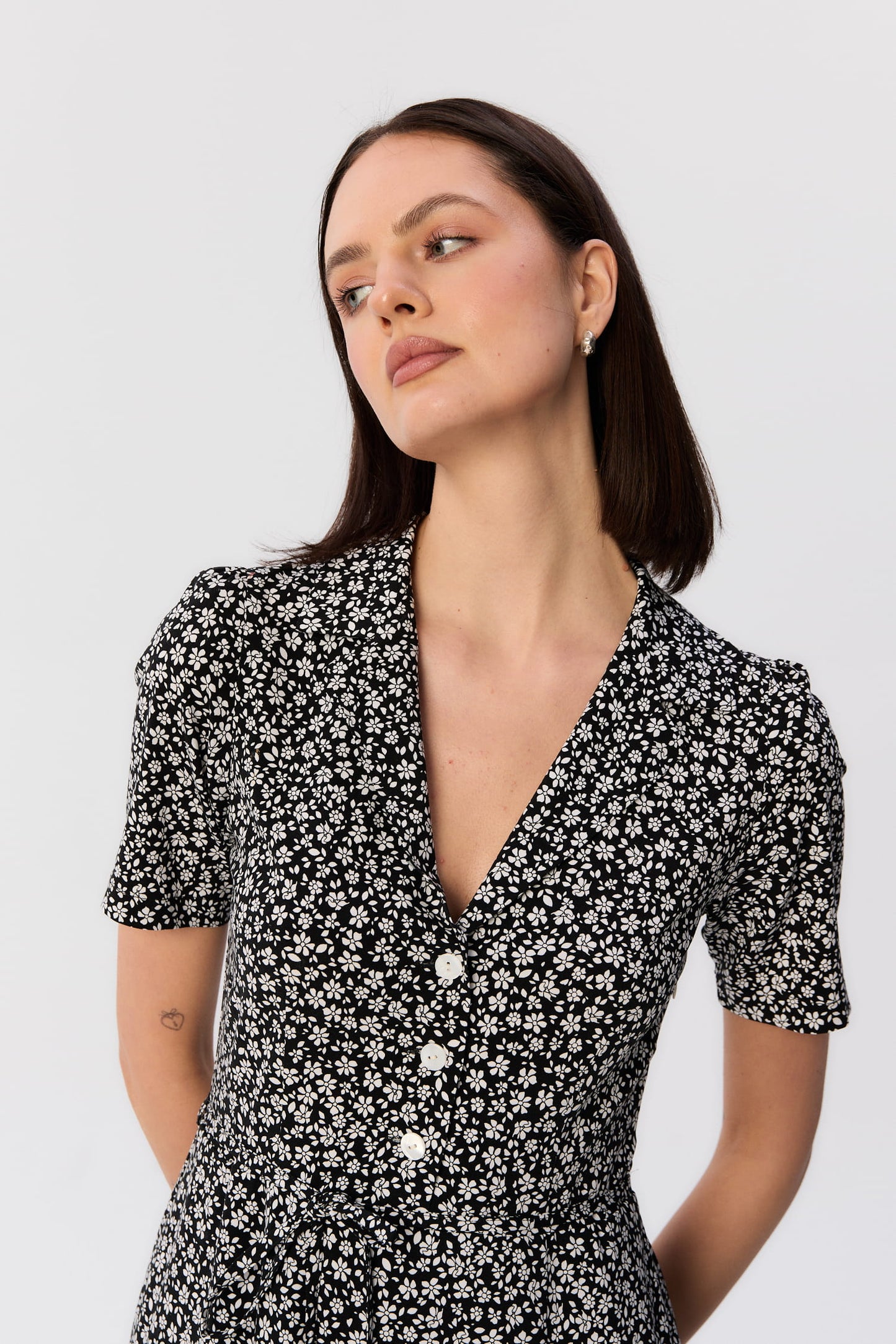 Zbliżenie na górę sukienki Bellucci od MAG NOLLY – czarno-biały kwiatowy print, dekolt w szpic i białe guziki w kobiecej stylizacji.